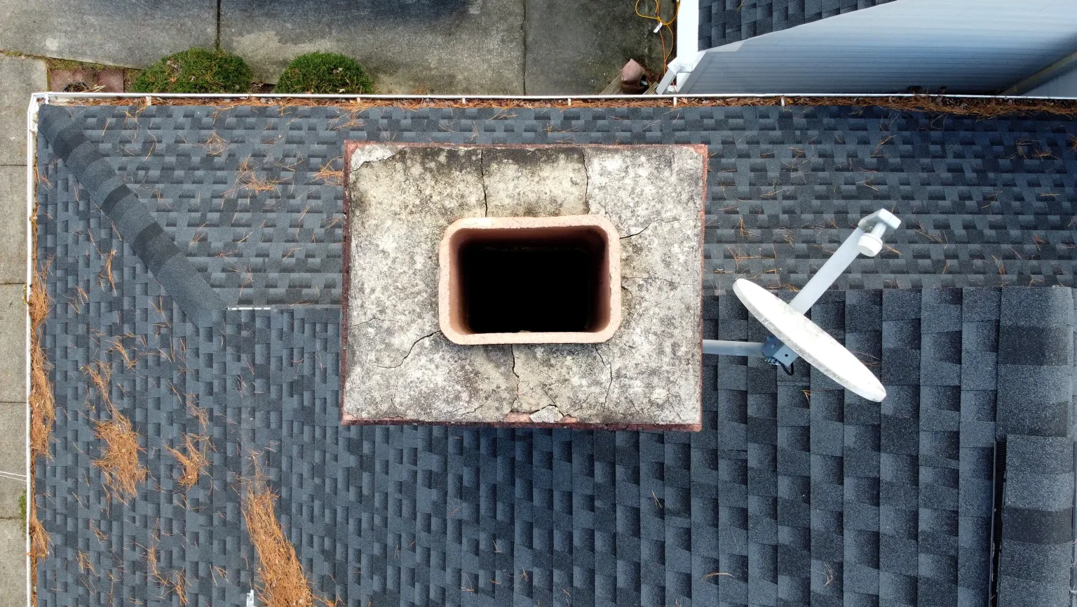 Aerial view of a damaged chimney crown with visible cracks and no cap — the kind of hidden damage a Level 2 inspection catches