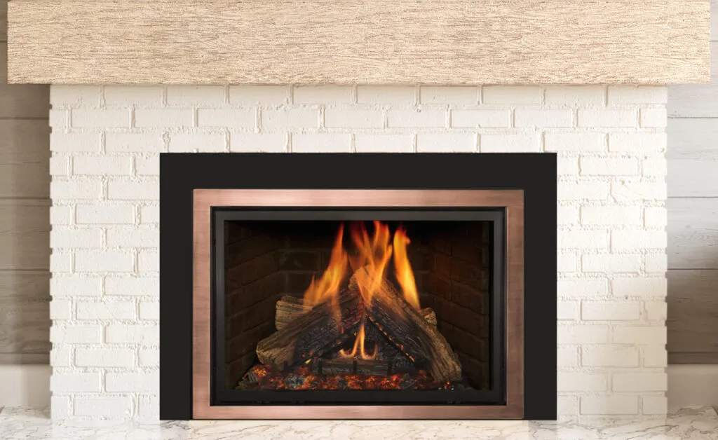 Gas fireplace insert in a white brick surround with copper trim